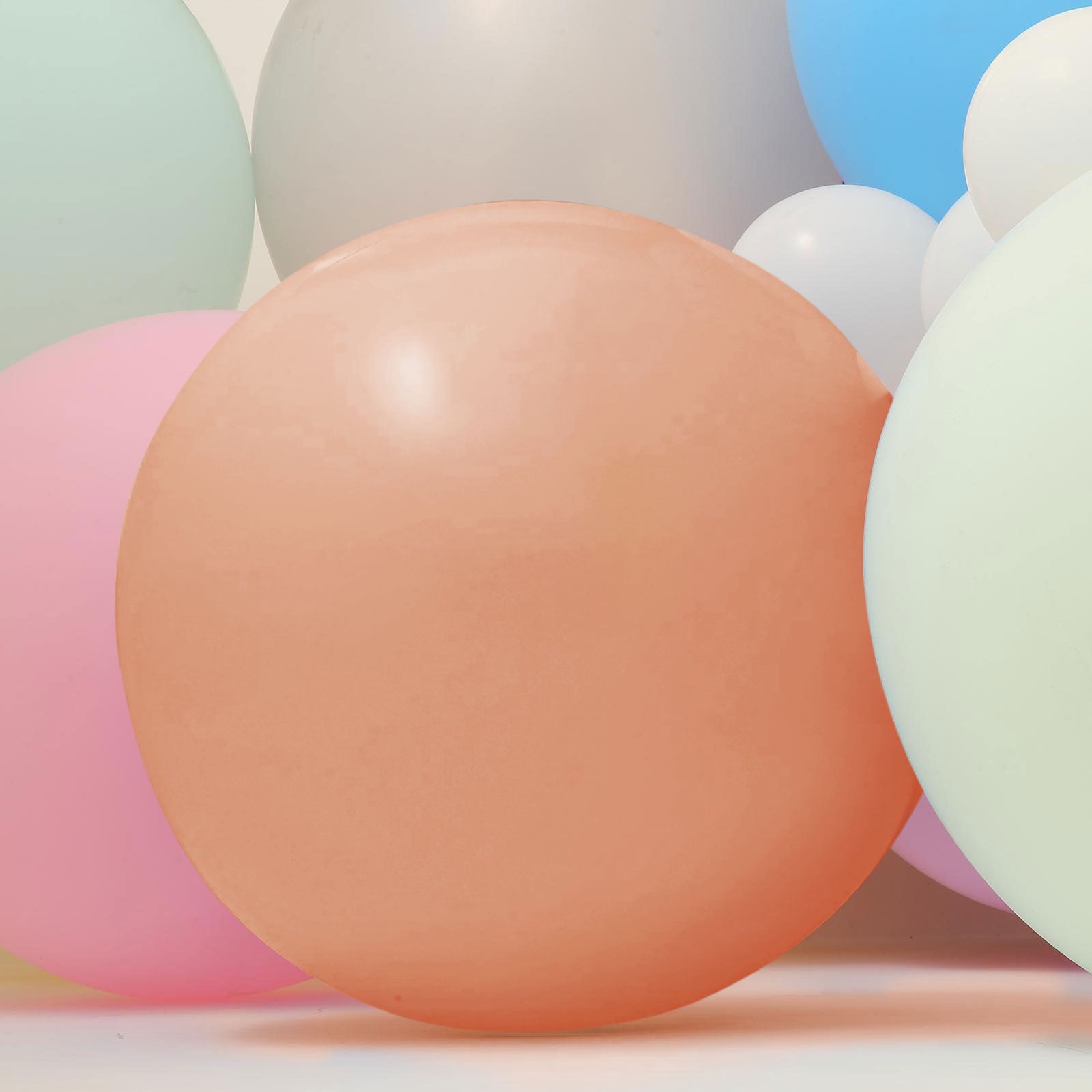 Large matte pastel balloons in soft peach and light green hues.