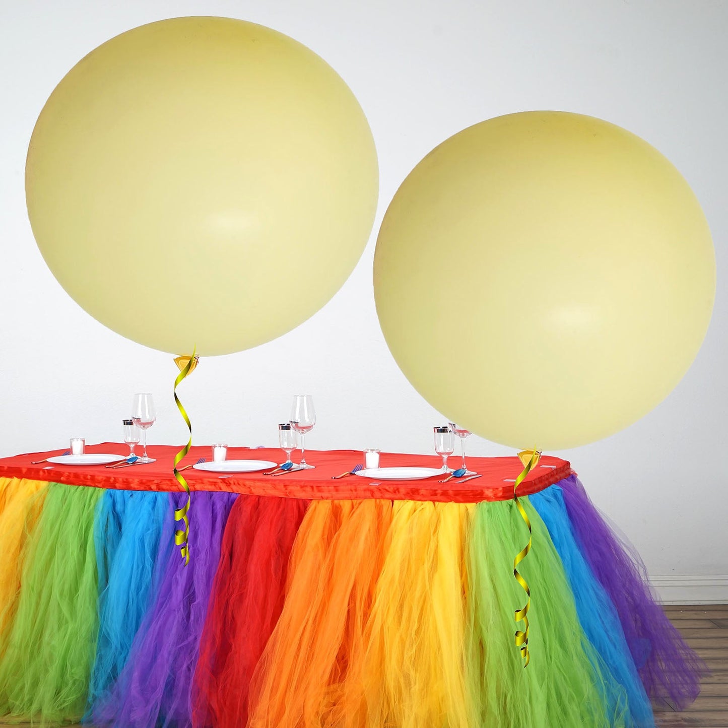 Pastel yellow large balloons on a festive table with colorful decorations.