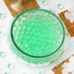 Large apple green jelly ball water bead vase fillers in a clear bowl.