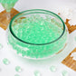Large apple green nontoxic jelly ball water beads in a clear vase.
