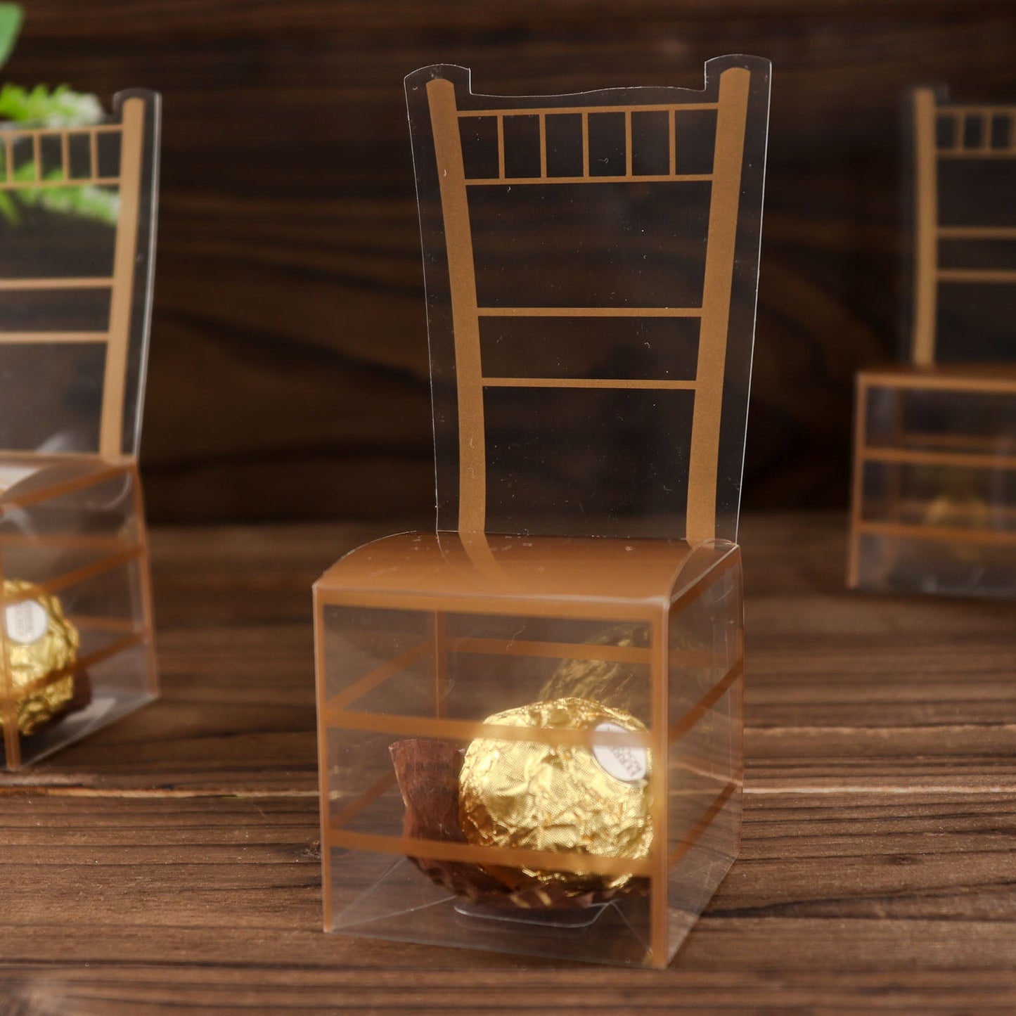 Clear and gold Chiavari chair-shaped candy gift box with treats inside.