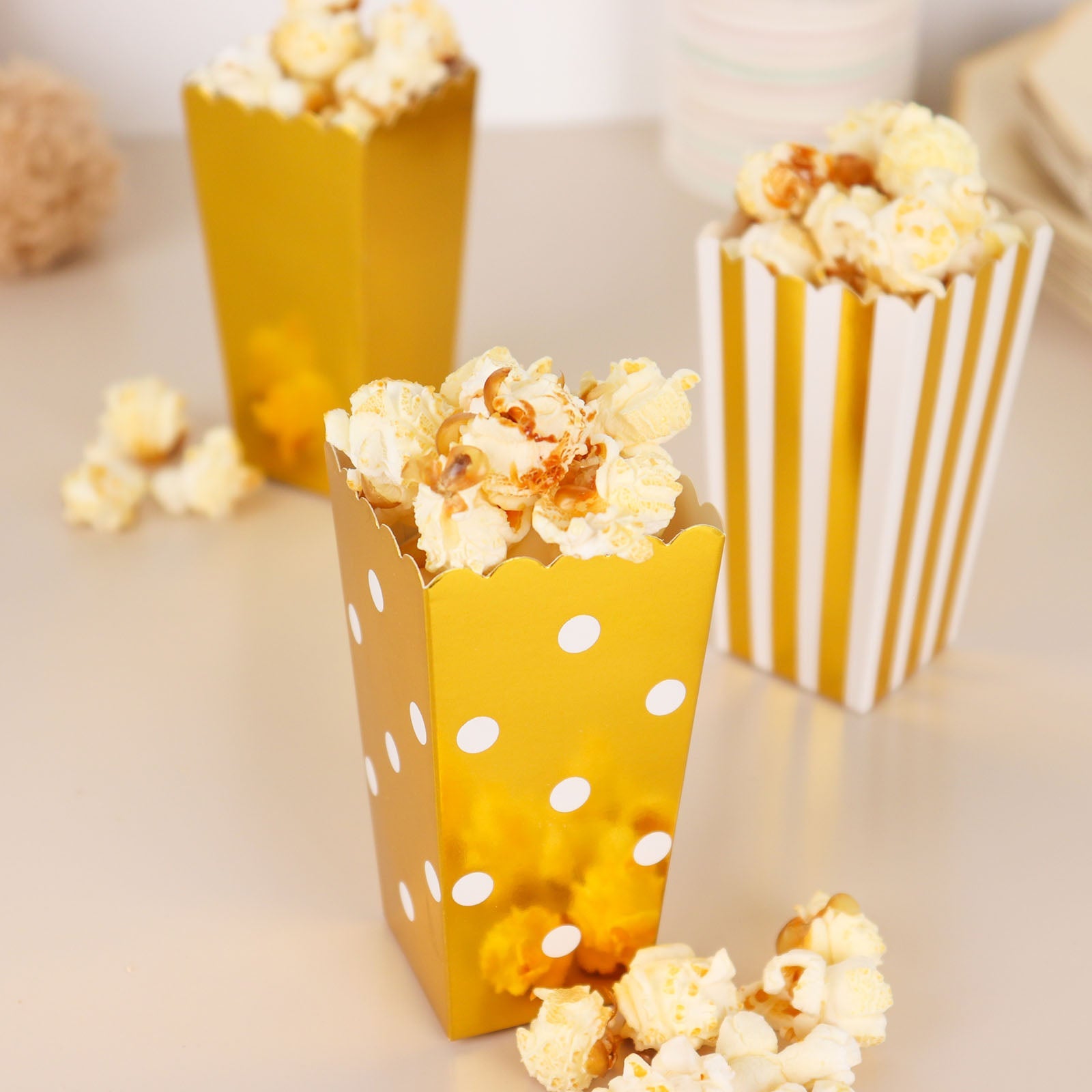 Gold and white popcorn favor boxes filled with popcorn.