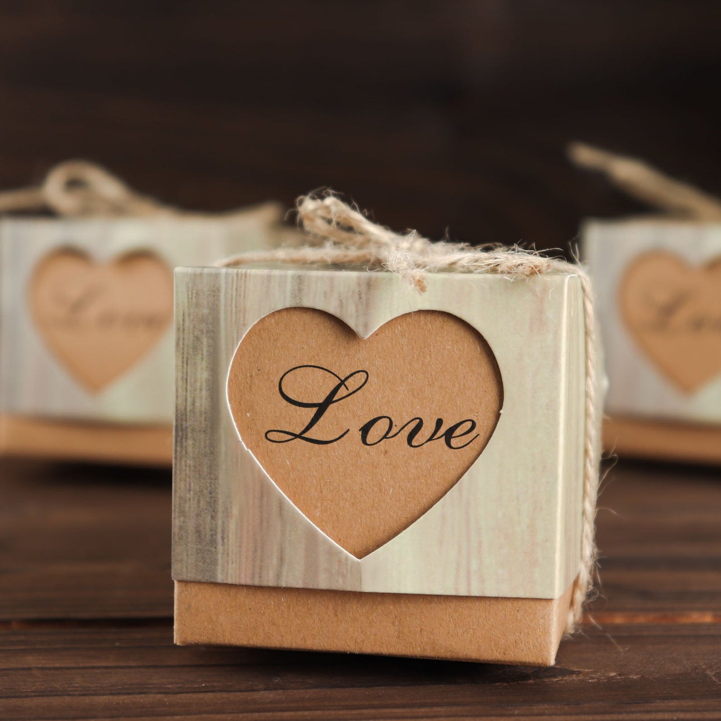 Natural brown square gift boxes with burlap twine and heart cut out.