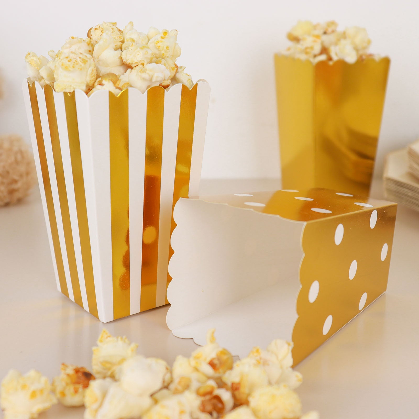 White and gold popcorn style favor boxes with striped and polka dot designs.