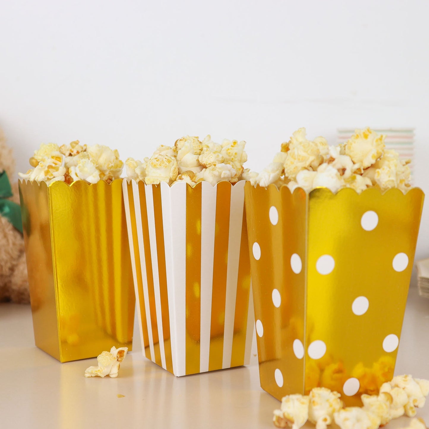 Gold and white popcorn style favor boxes with candy inside.