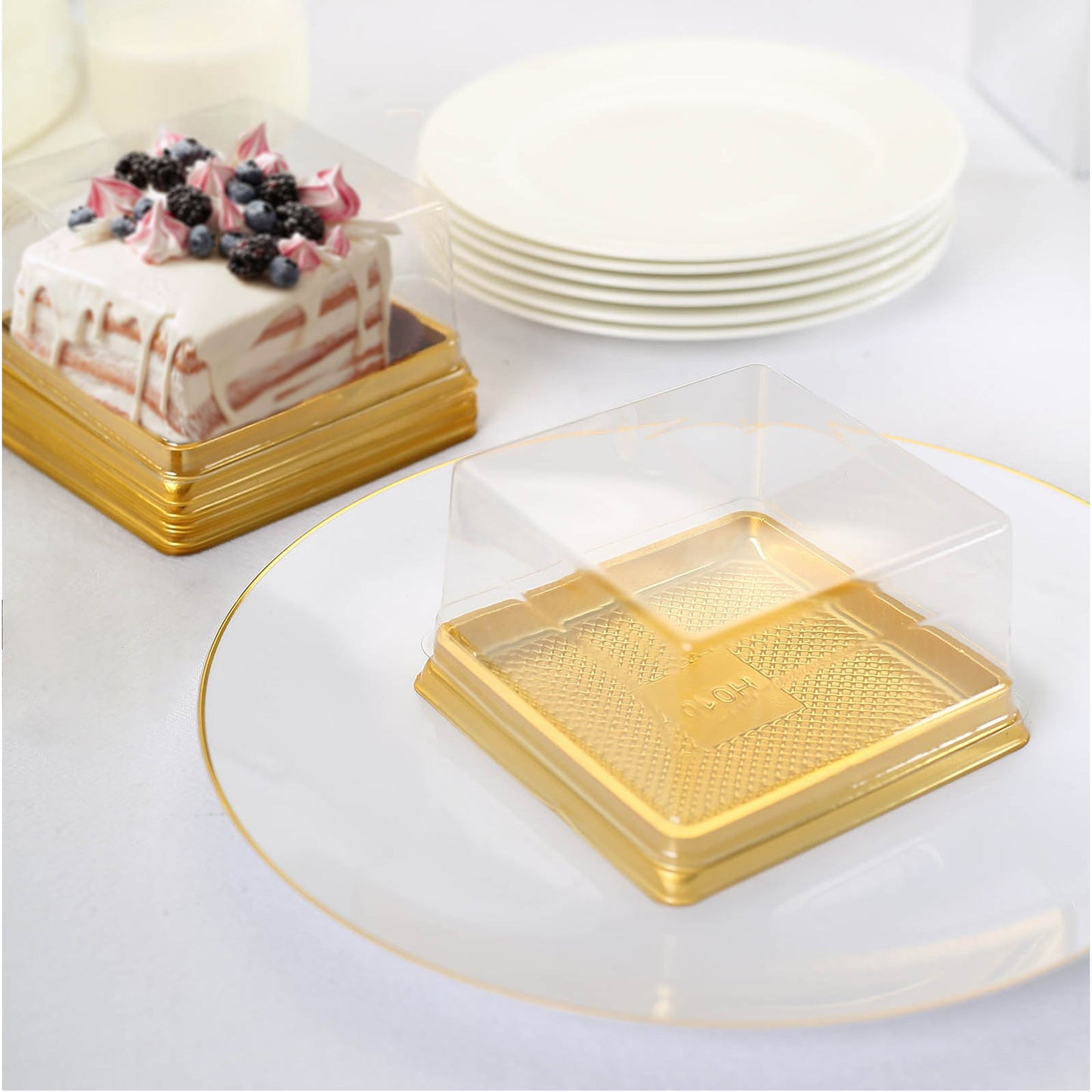Clear gold square mini dessert boxes on a white plate.