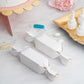 White candy-shaped gift boxes with satin ribbon for party favors.