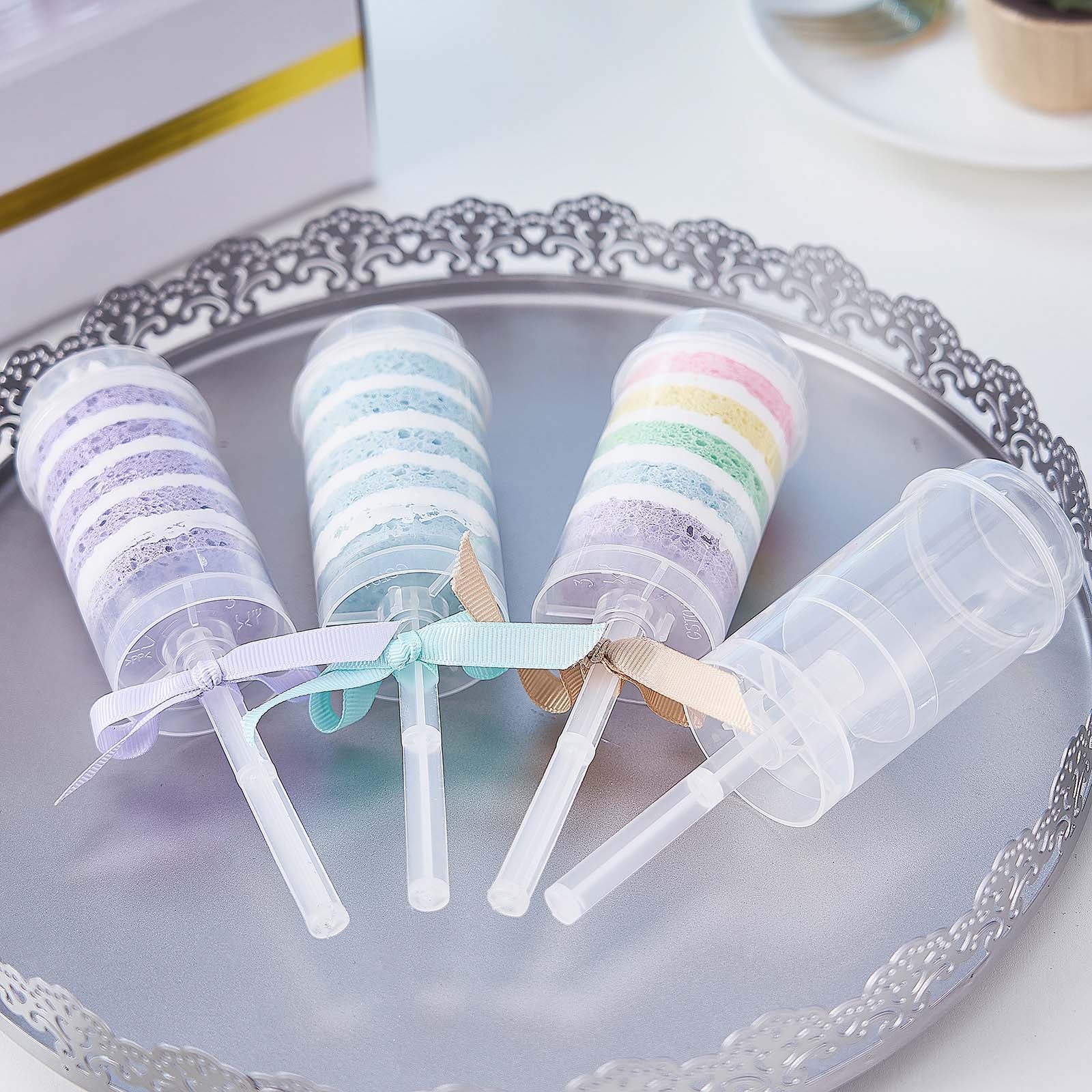 Clear plastic push-up cake pop set with pastel colors on a decorative tray.