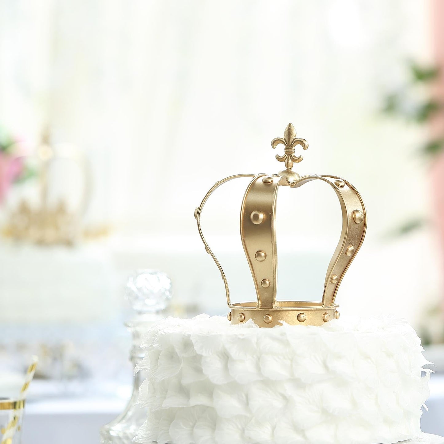 Gold metal crown cake topper with fleur-de-lis design.