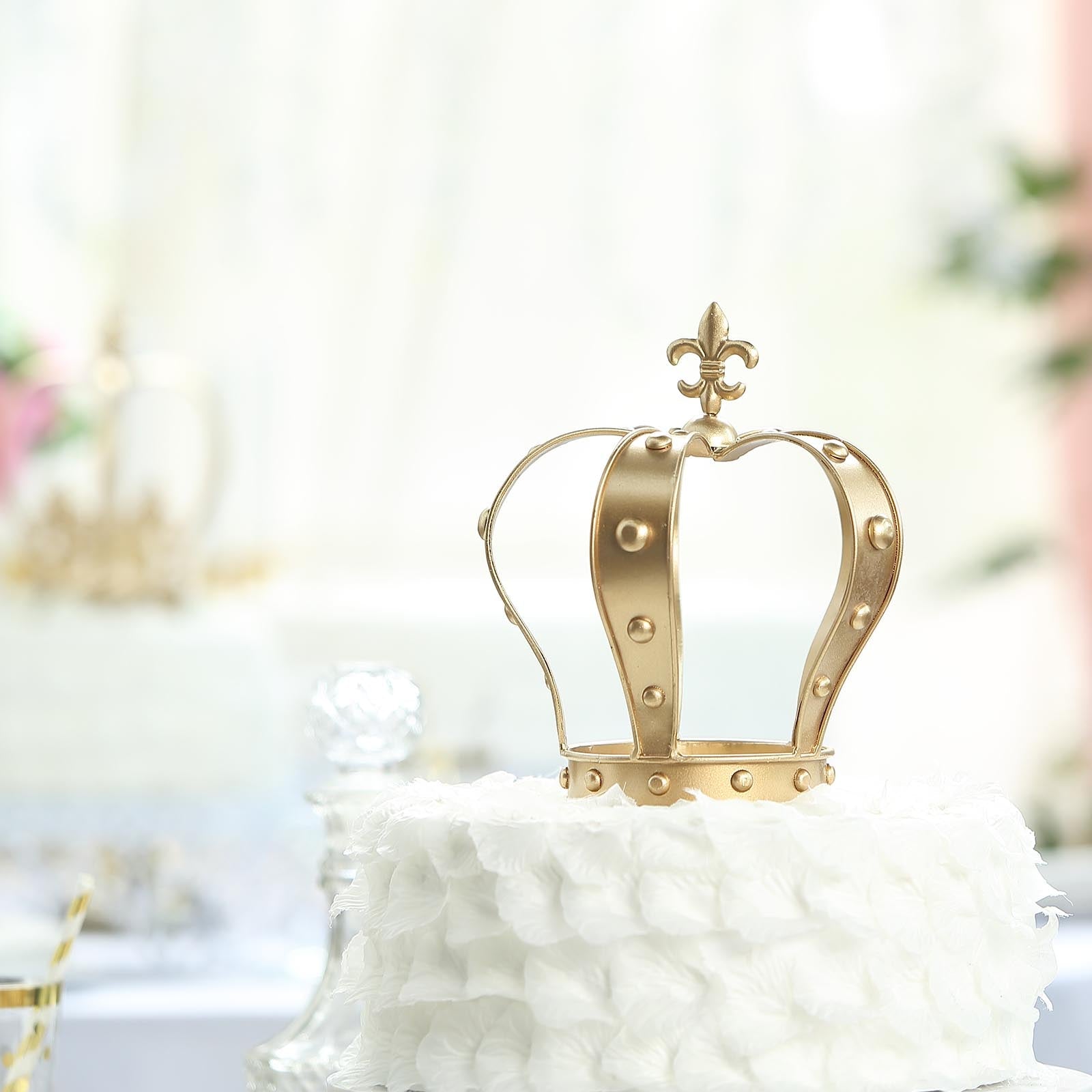 Gold metal crown cake topper with fleur-de-lis design.