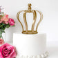 Matte gold metal royal crown cake topper on a white wedding cake.