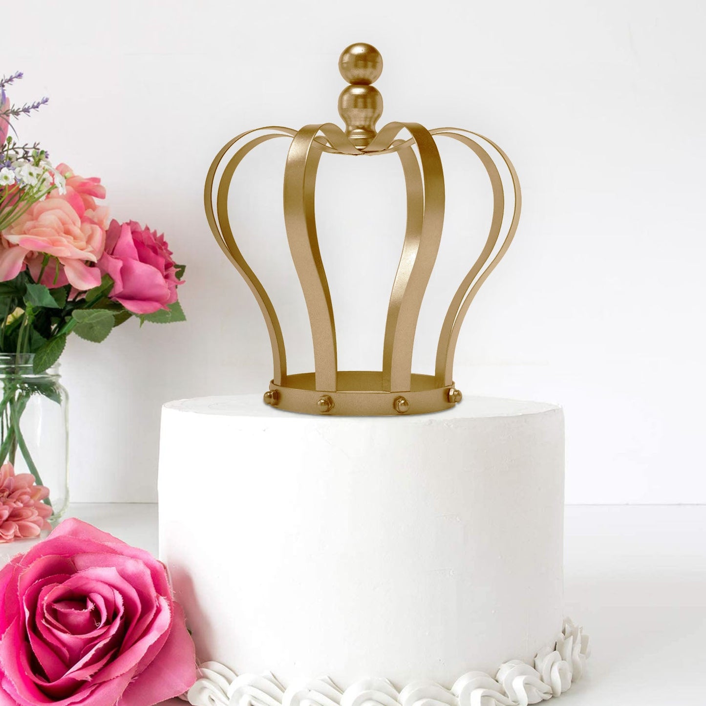 Matte gold metal royal crown cake topper on a white wedding cake.