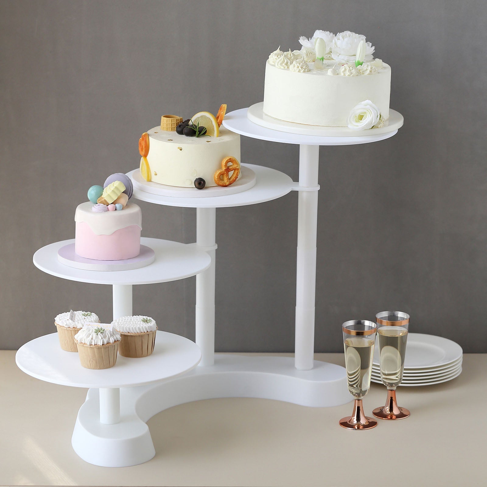 White 4-tier half moon cake and dessert stand with assorted treats.