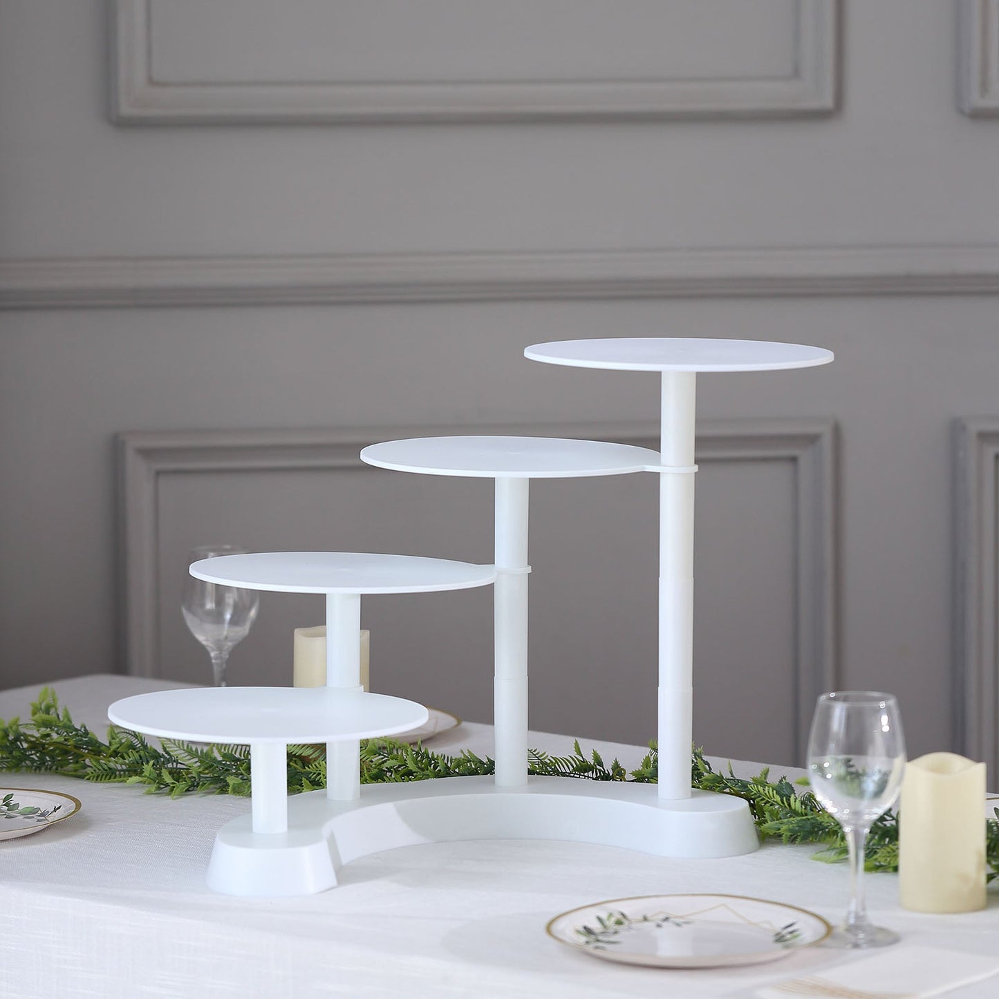 White 4-tier half moon plastic cake stand for displaying desserts.