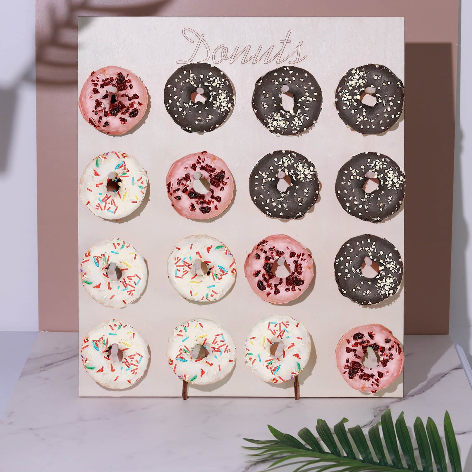 Donut bar display stand with pink and chocolate donuts on a beige background.