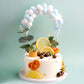 Blue mini arch shape cotton ball cake topper on a decorated cake.