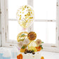 Gold birthday cake topper with mini paper fans and confetti balloon decor.