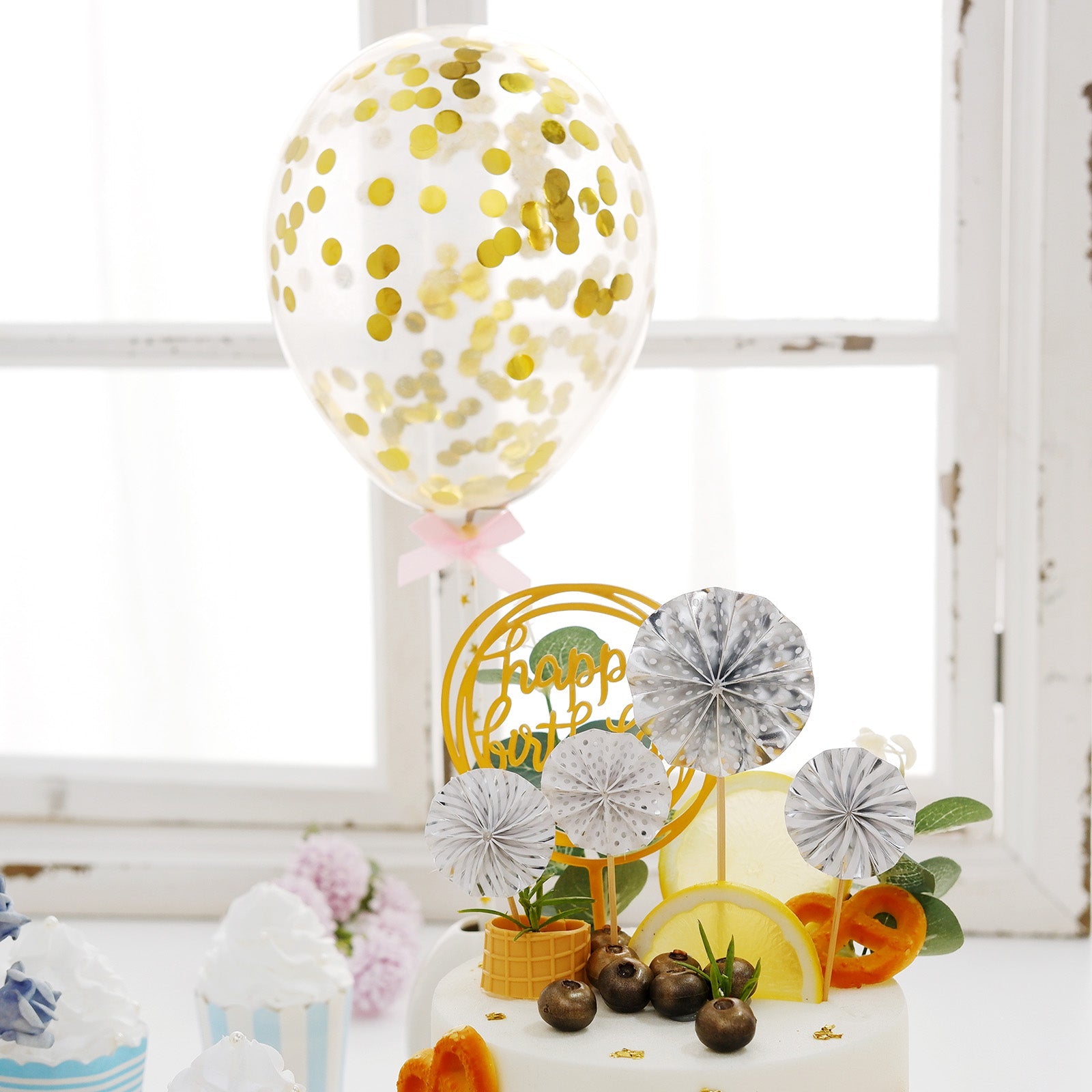Gold and silver birthday cake topper with mini fans and confetti balloon decor.