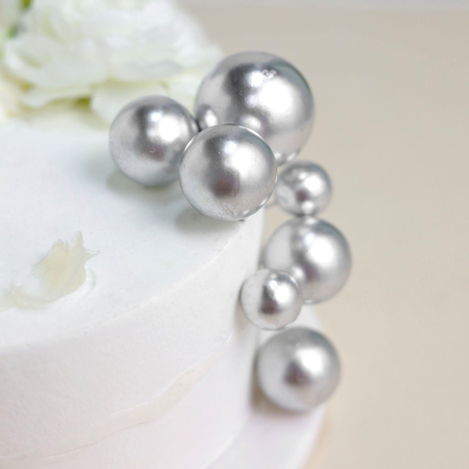 Silver faux pearl balls cake topper picks on a white cake.