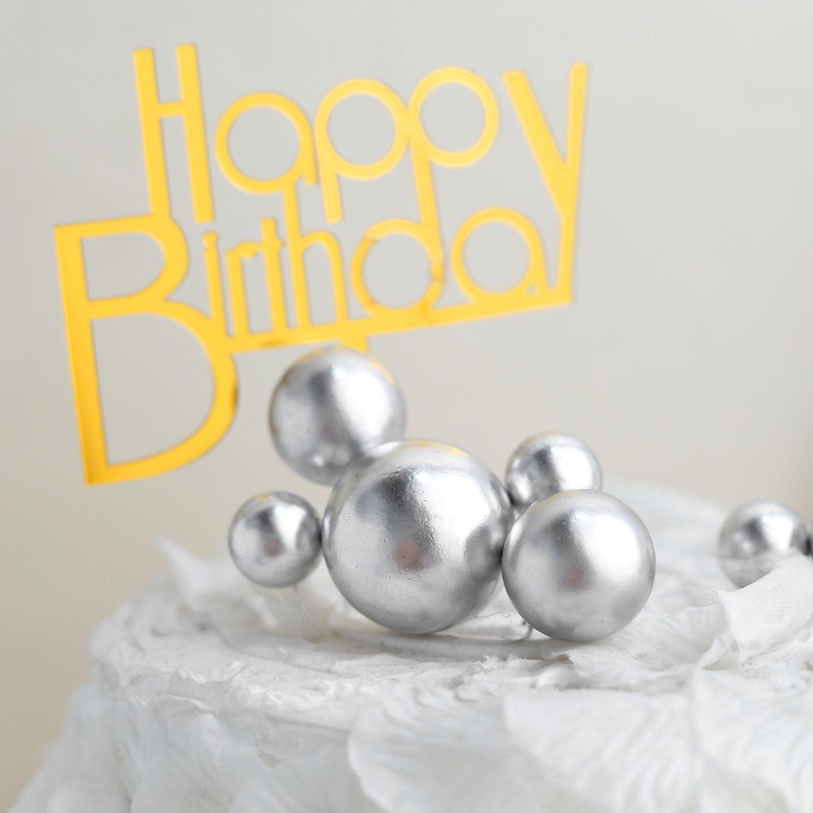 Silver faux pearl cake topper picks on a decorated birthday cake.