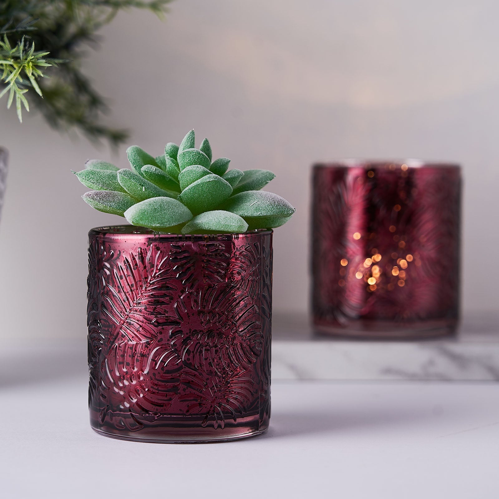 Burgundy mercury glass palm leaf candle holders with succulent decor.