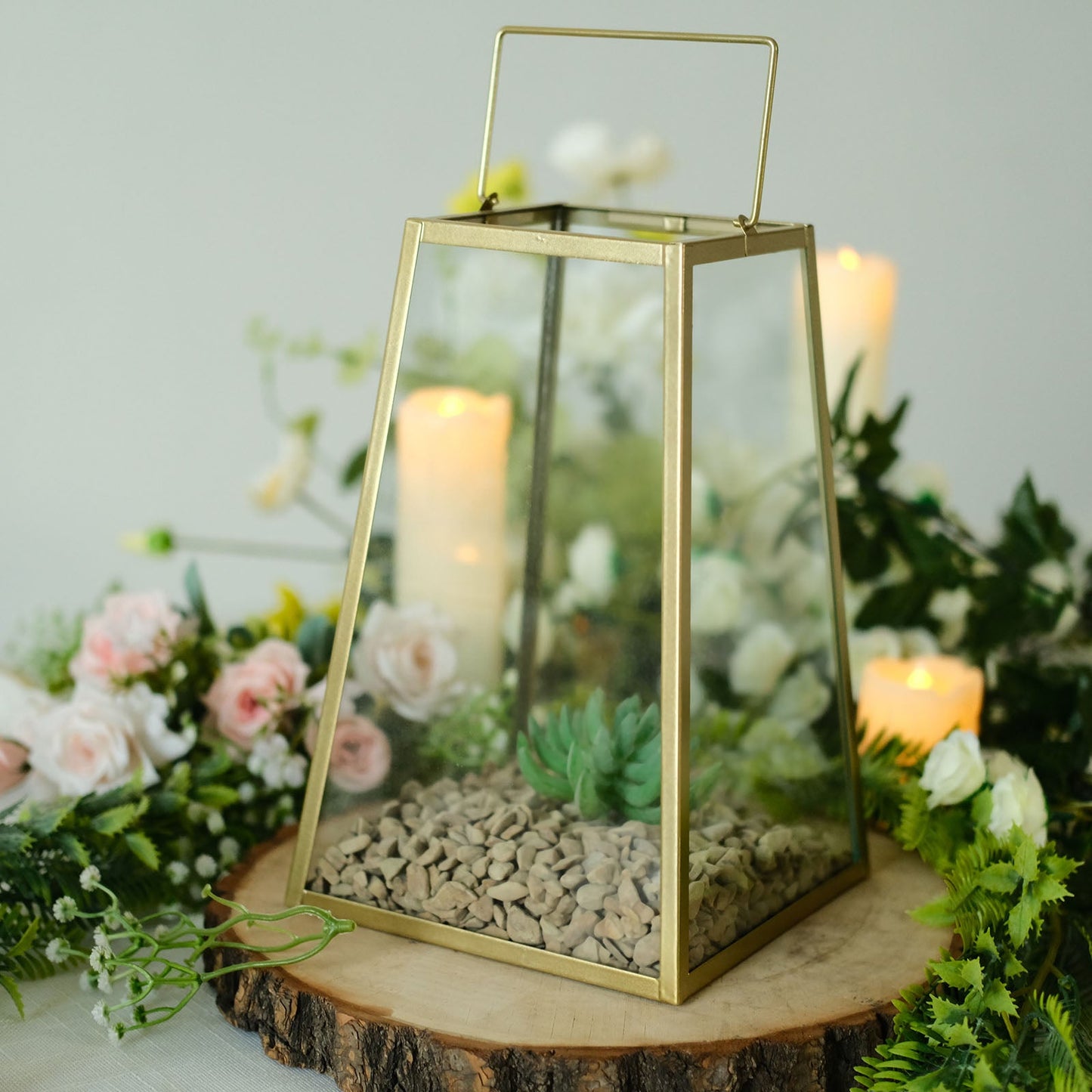 Gold trapezoid metal candle lantern with geometric design and succulent planter.