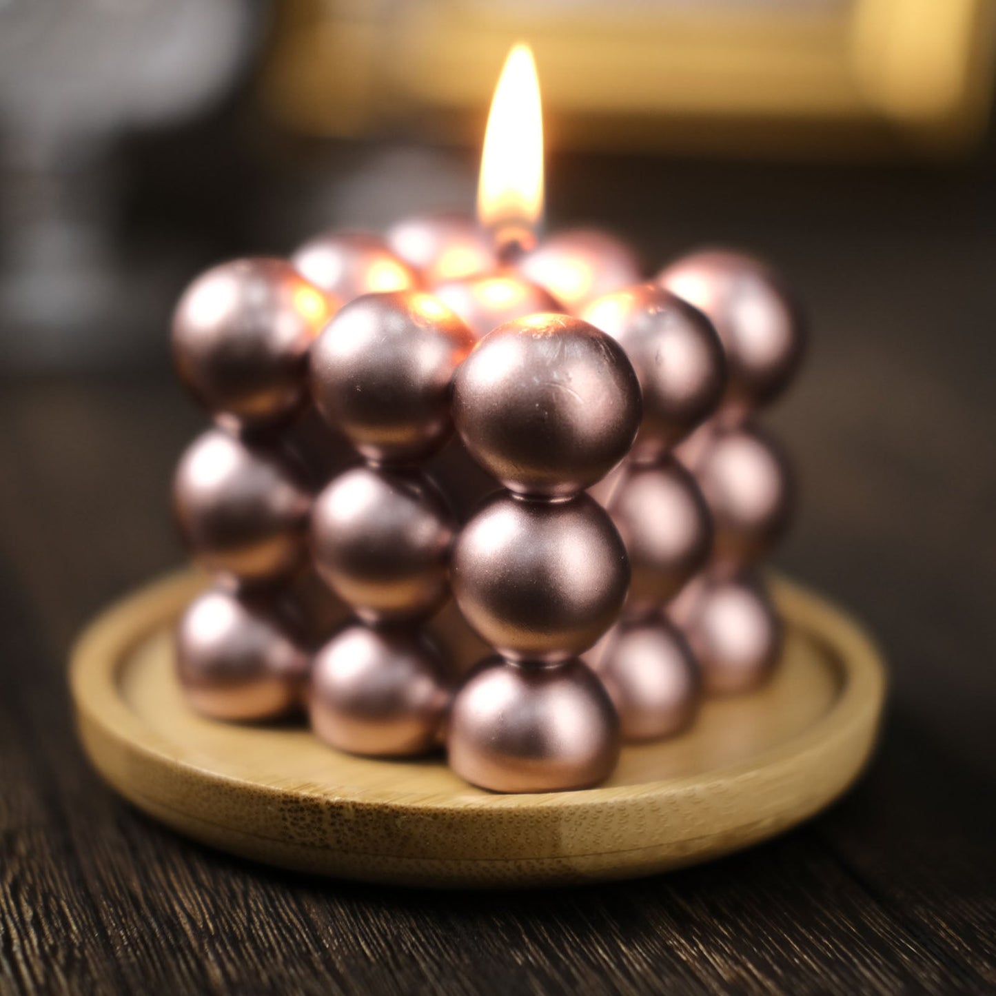 Metallic rose gold bubble cube candle set on a wooden tray.
