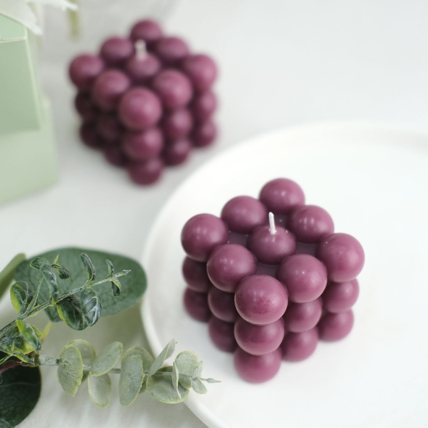 Burgundy bubble cube decorative candles on a white plate.