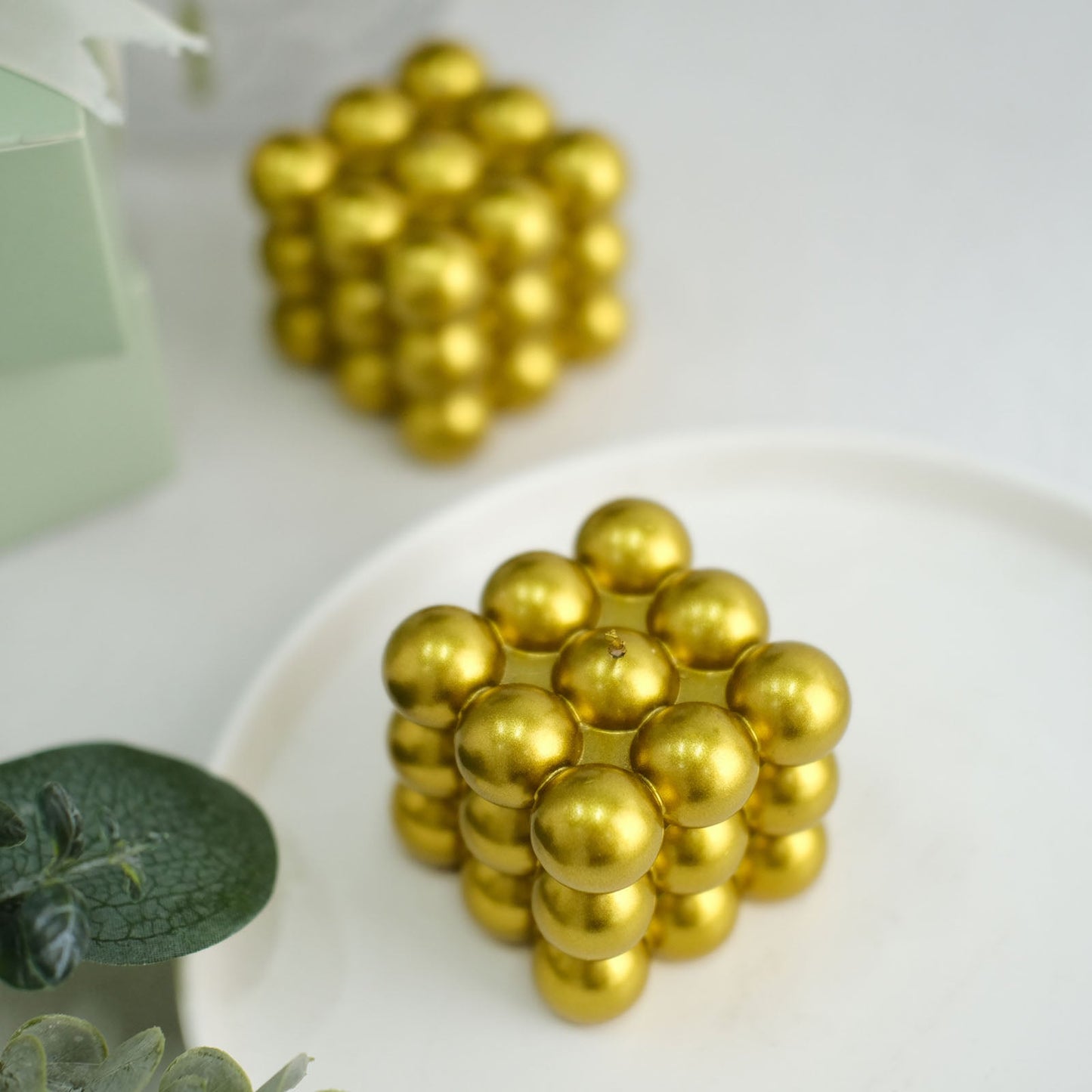 Metallic gold bubble cube decorative candles on a plate.