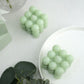 Sage green bubble cube decorative candles on a white plate.