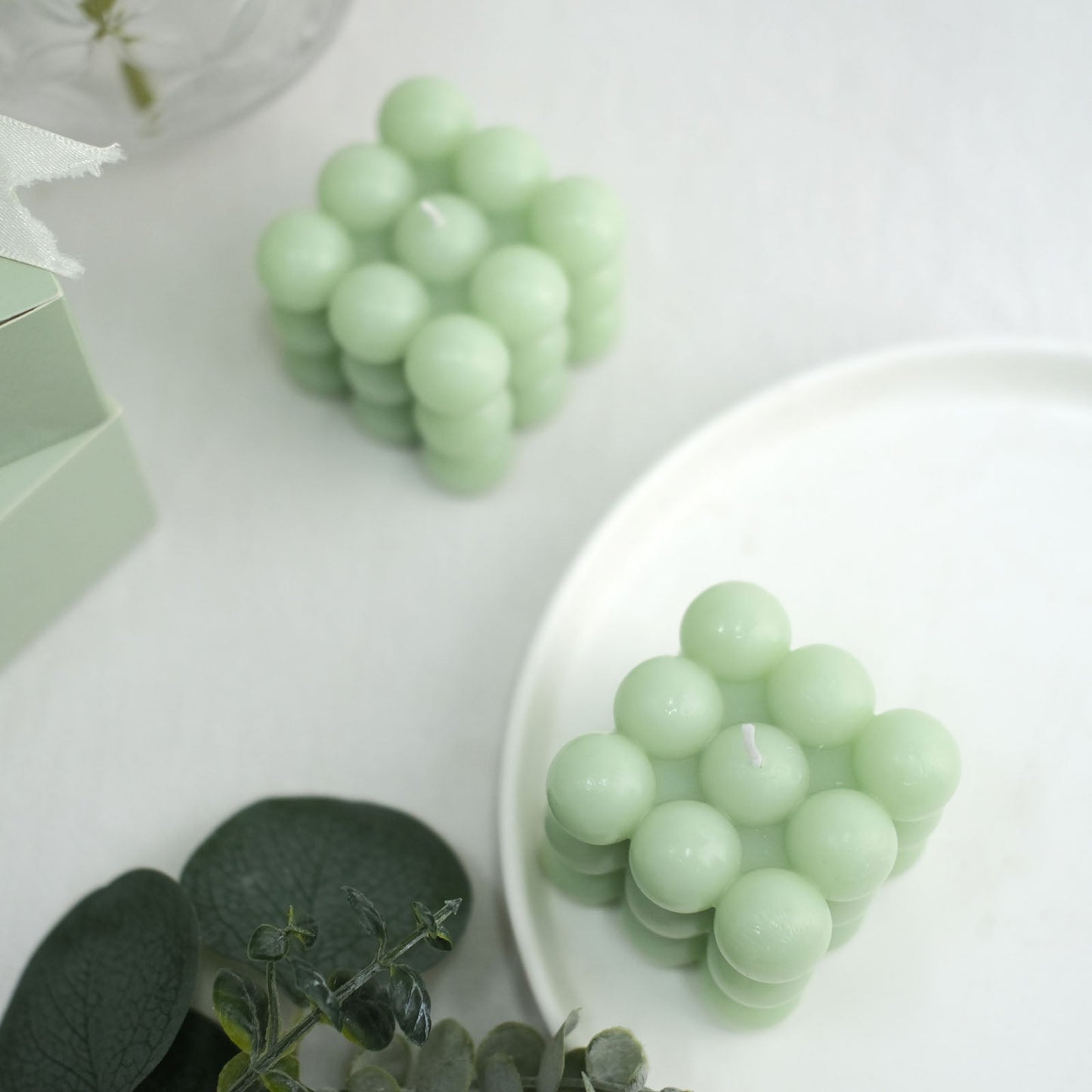 Sage green bubble cube decorative candles on a white plate.