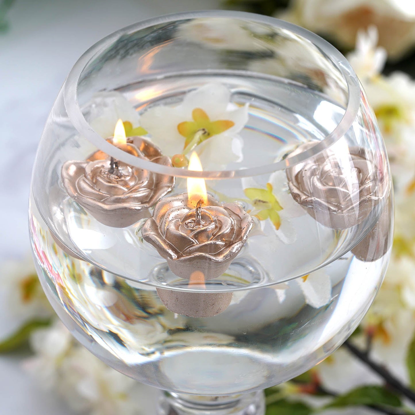 Rose gold mini rose floating candles in clear water vase.