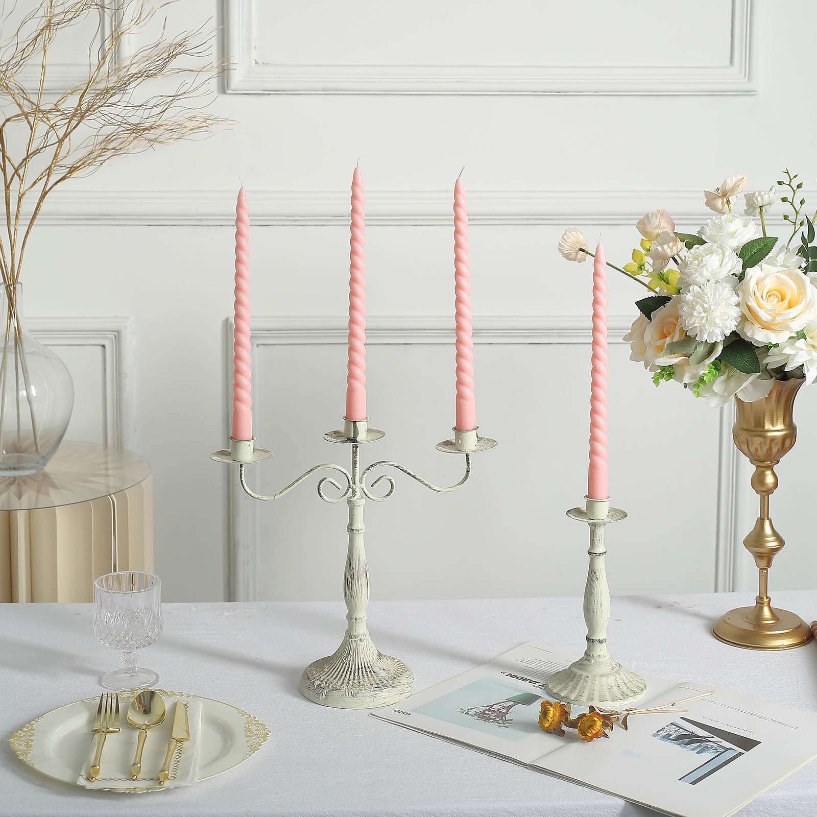 Blush pink spiral taper candles on a decorative candle holder.