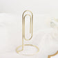 Gold metal paperclip card holder stand for table numbers and menus.