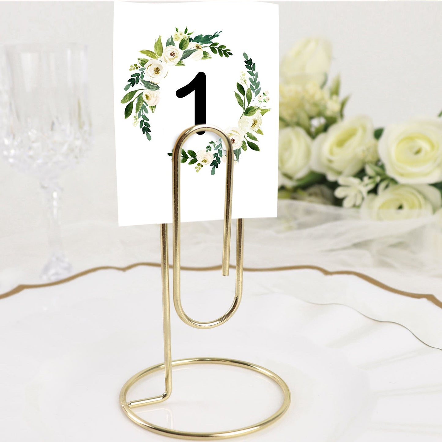 Gold metal paperclip card holder stand with table number display.
