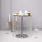 Metallic silver cake stand with crystal chains and desserts on top.