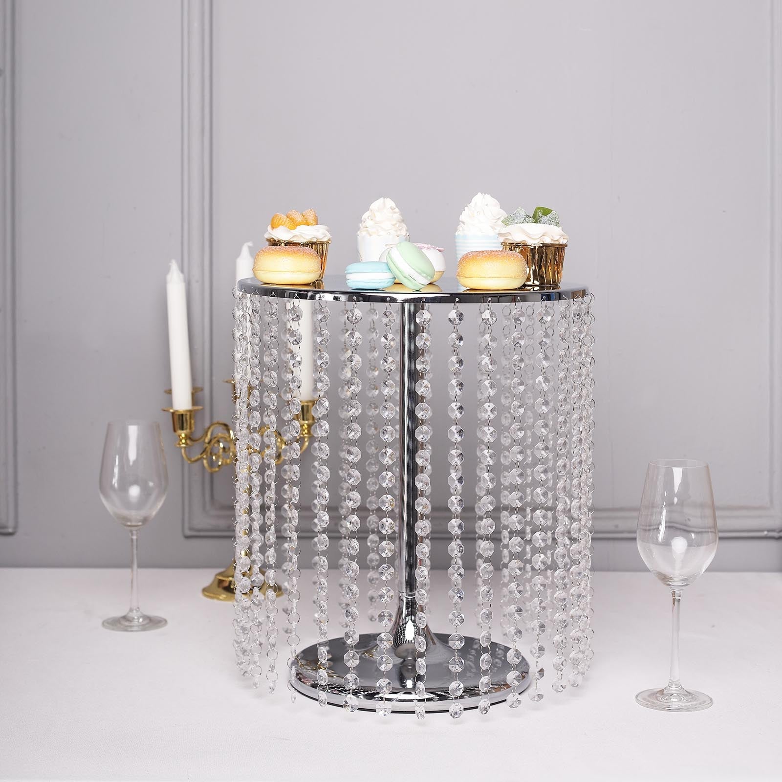 Metallic silver cake stand with crystal chains and desserts on top.