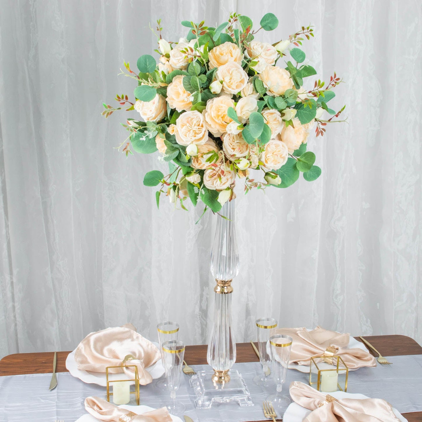Gold acrylic crystal pillar candle stand with floral arrangement centerpiece.