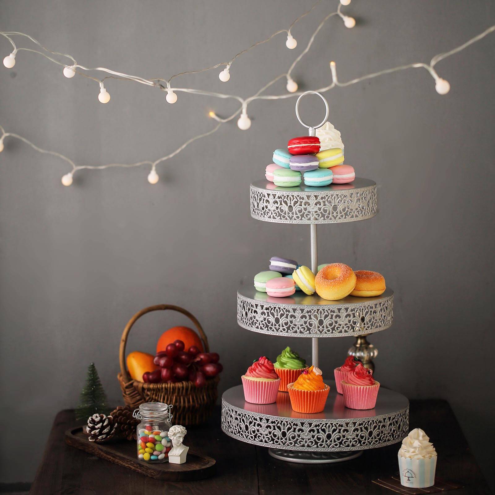 Silver 3-tier cupcake stand with colorful desserts on display.