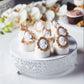 White metal round cake stand with elegant floral design, perfect for weddings.