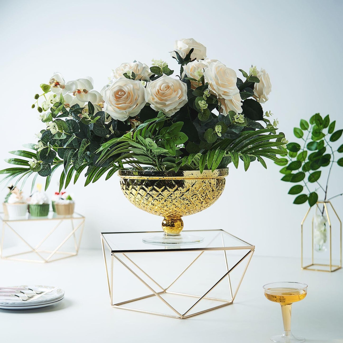 Gold geometric cake stand with square glass top, perfect for elegant displays.