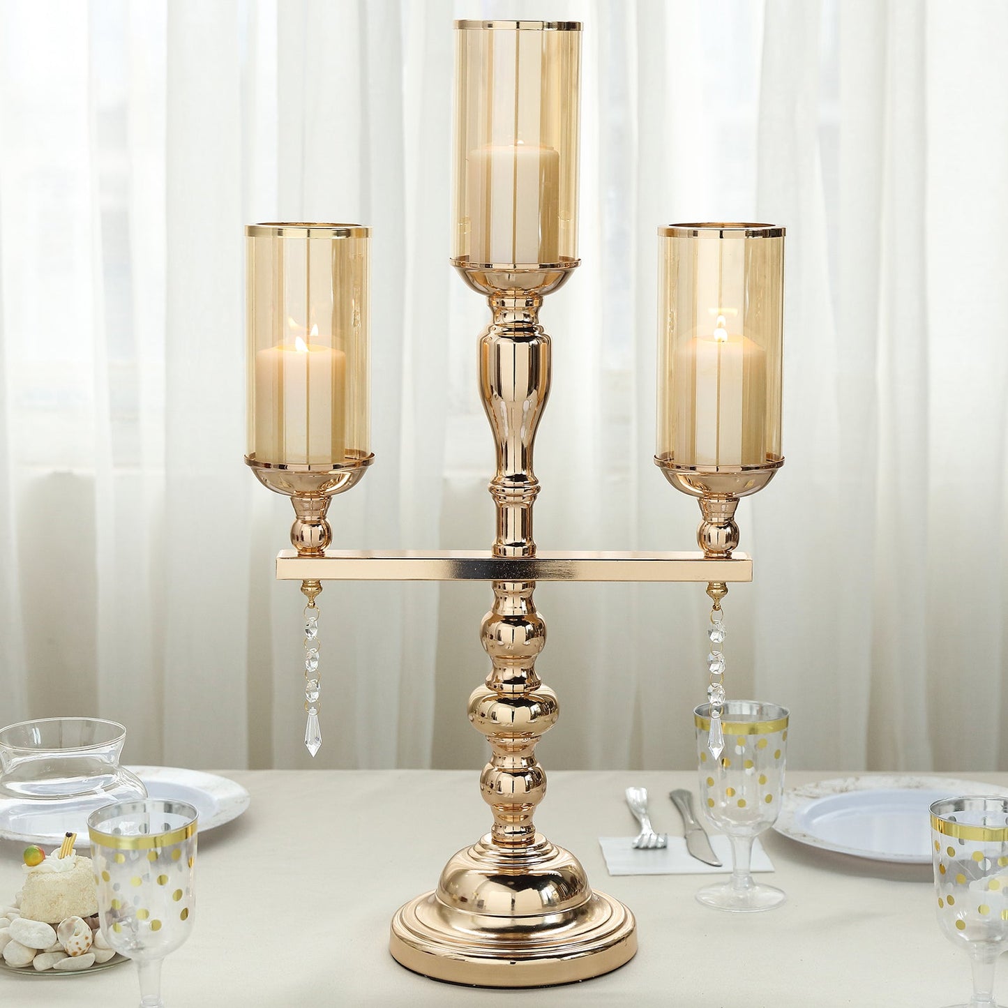 Gold metal 3 arm candelabra with amber glass shades and hurricane candle holders.