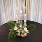 Clear crystal candelabra with floral arrangement and candles on a round table.