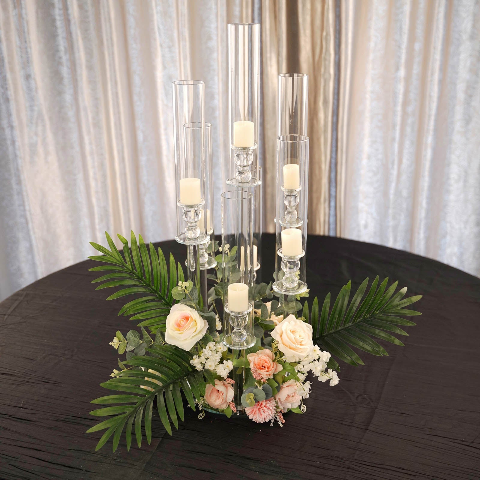 Clear crystal candelabra with floral arrangement and candles on a round table.