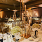 Gold 12-arm taper candle holder with clear glass shades in elegant setting.