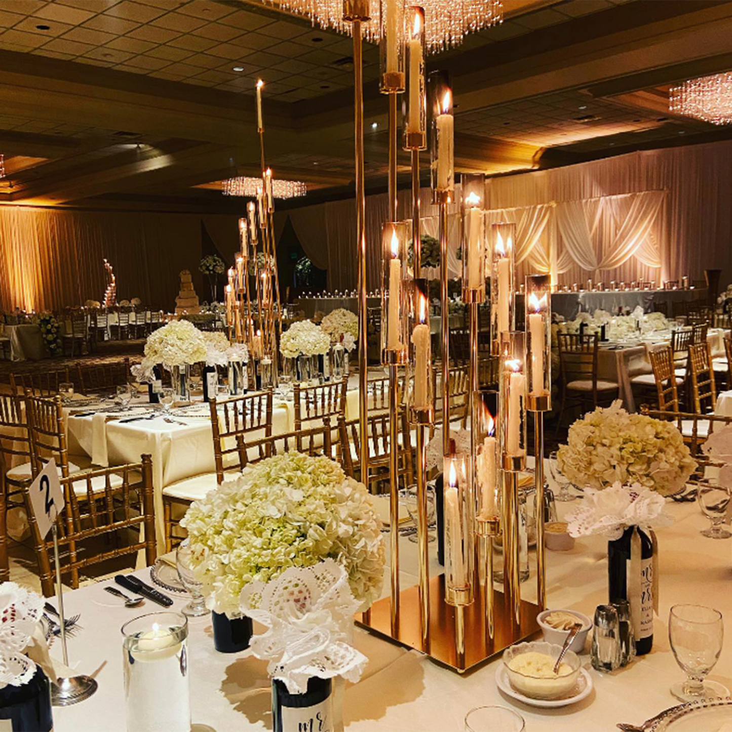 Gold 12-arm taper candle holder with clear glass shades in elegant setting.