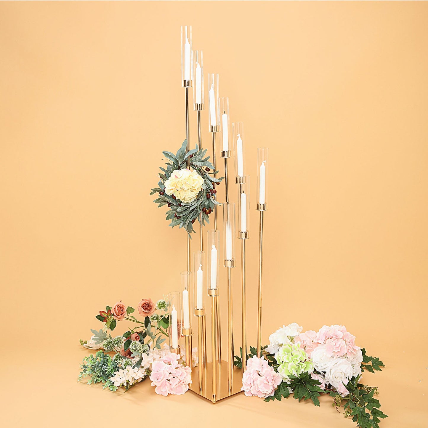 Gold taper candle holder with clear glass shades and floral arrangement.