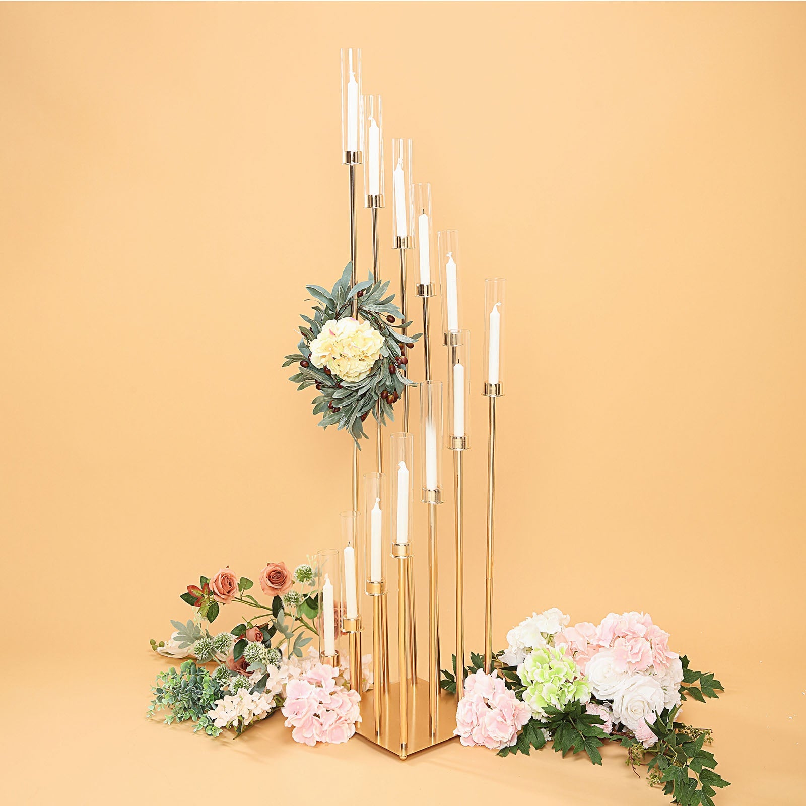 Gold taper candle holder with clear glass shades and floral arrangement.