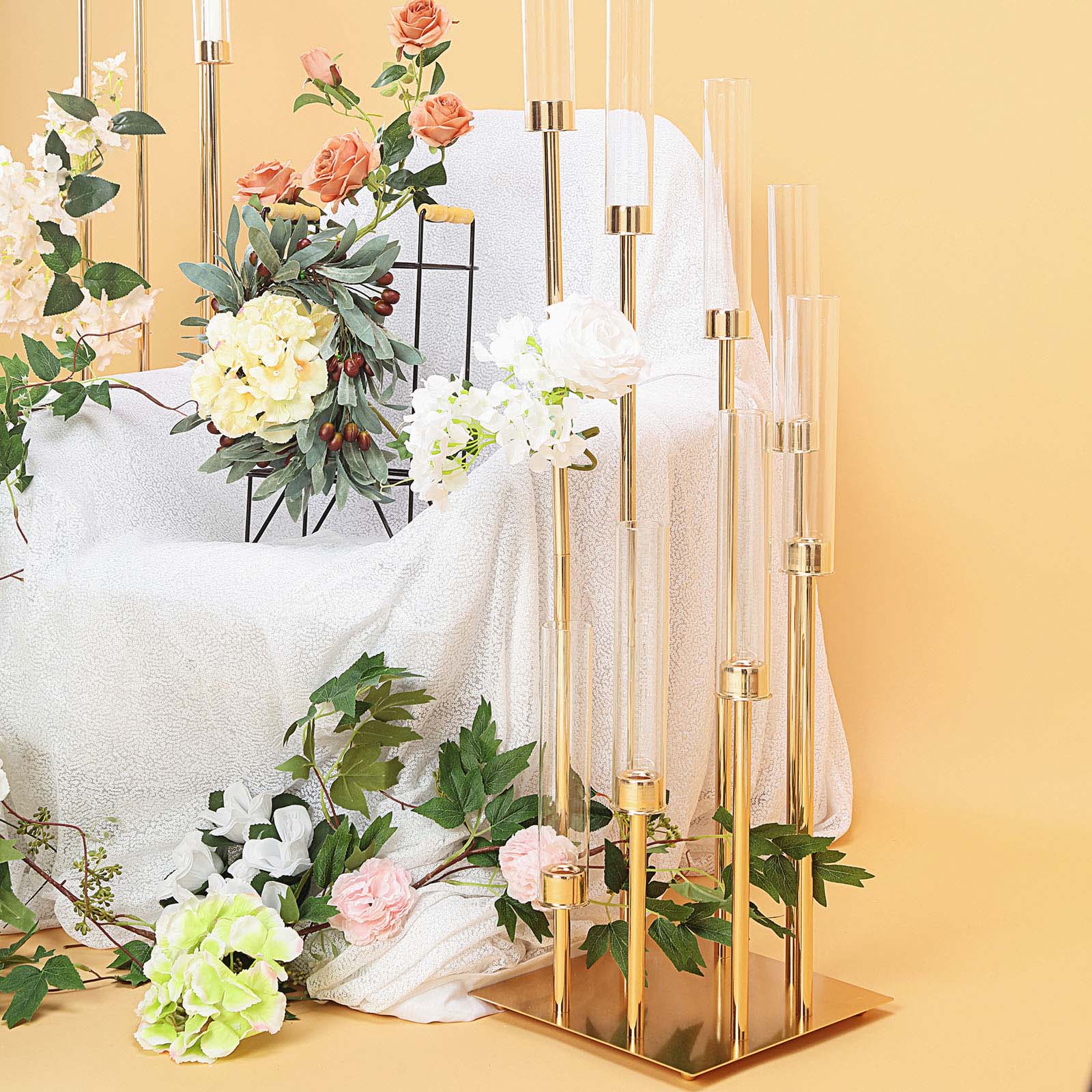 Gold 8 arm taper candle holder with clear glass shades and floral arrangement.