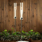 24" tall silver metal candlestick holders with glass chimneys, featuring lit candles.